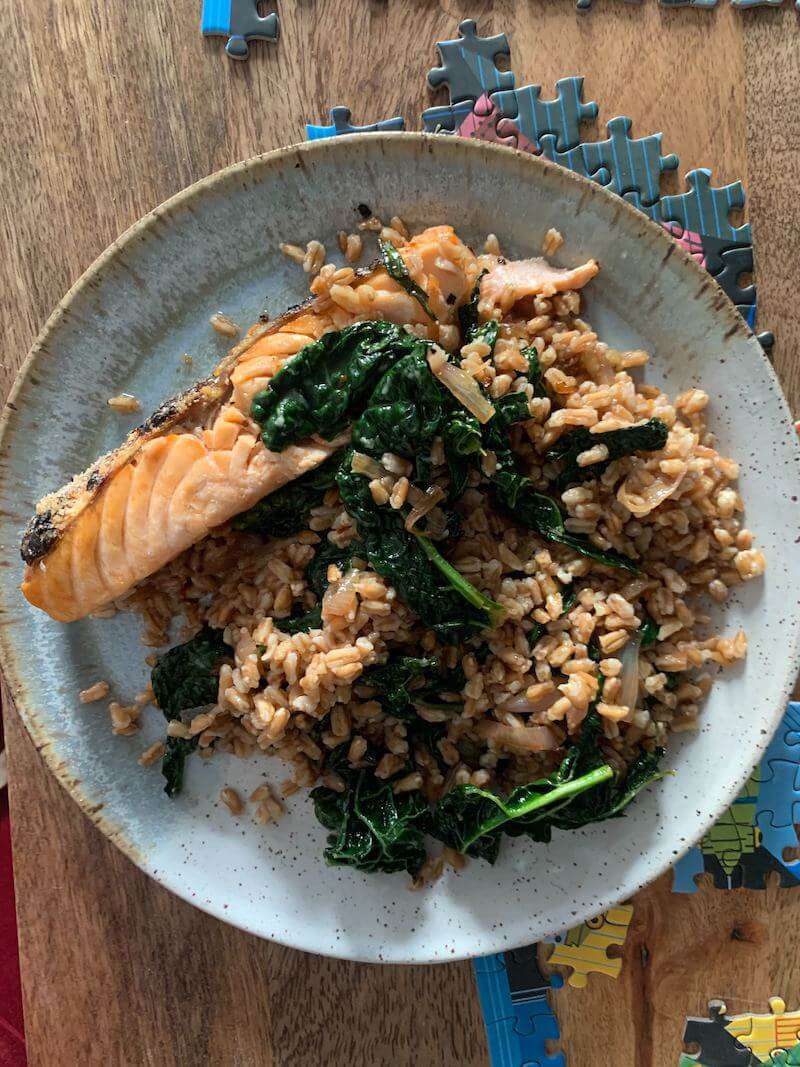 Overhead view of plate of farro and salmon on top of disparate puzzle pieces