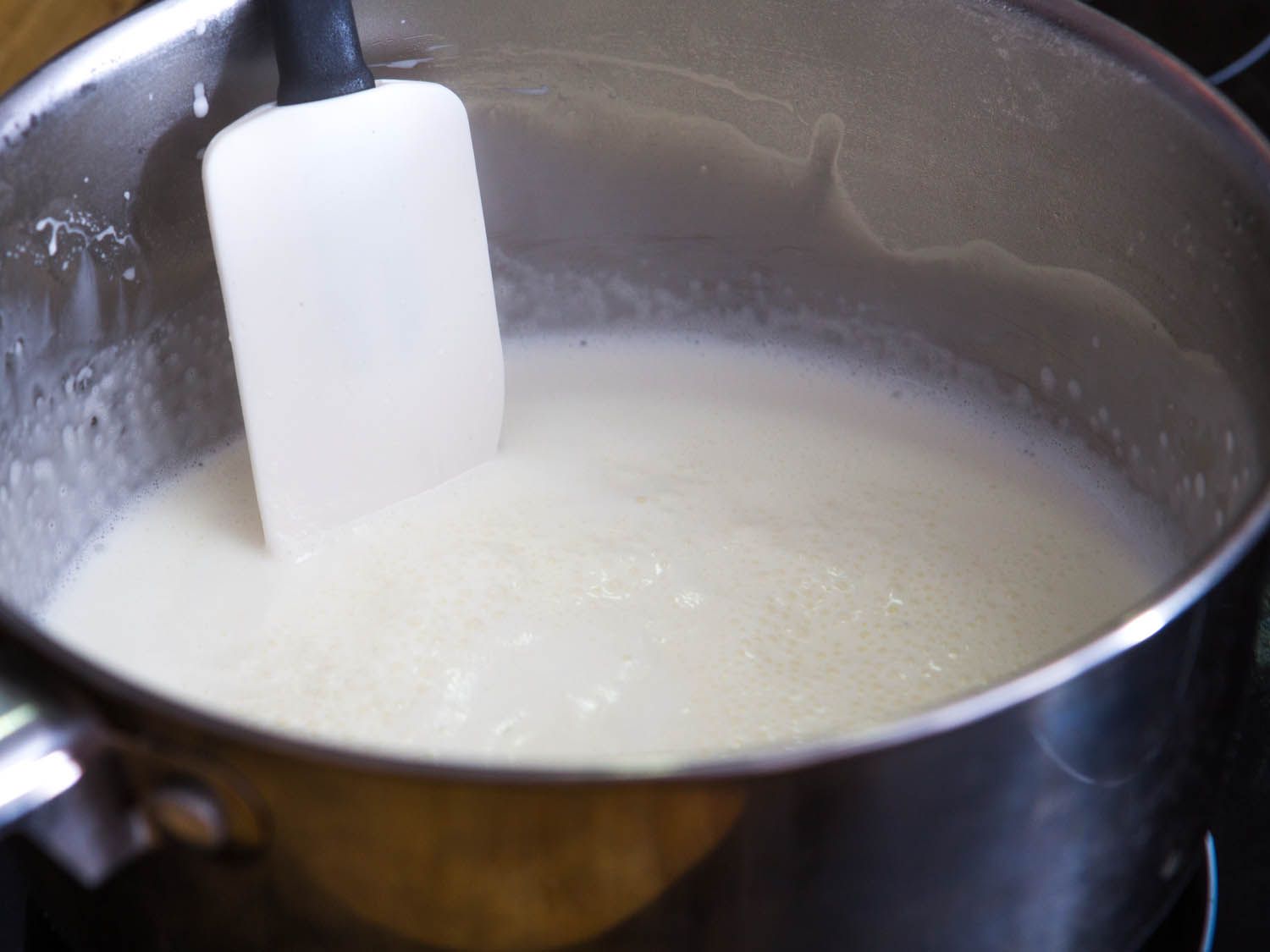 Premade mashed potatoes being stirred into heated liquid.