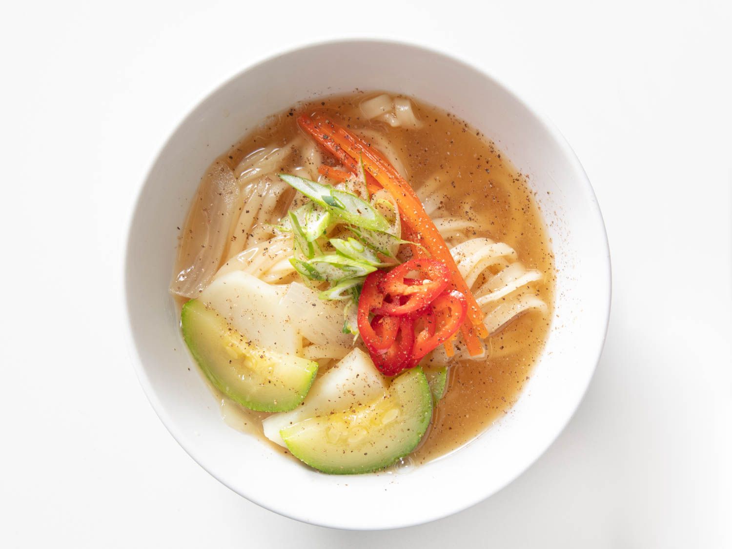 Finished bowl of myeolchi kal guksu, garnished with scallions.