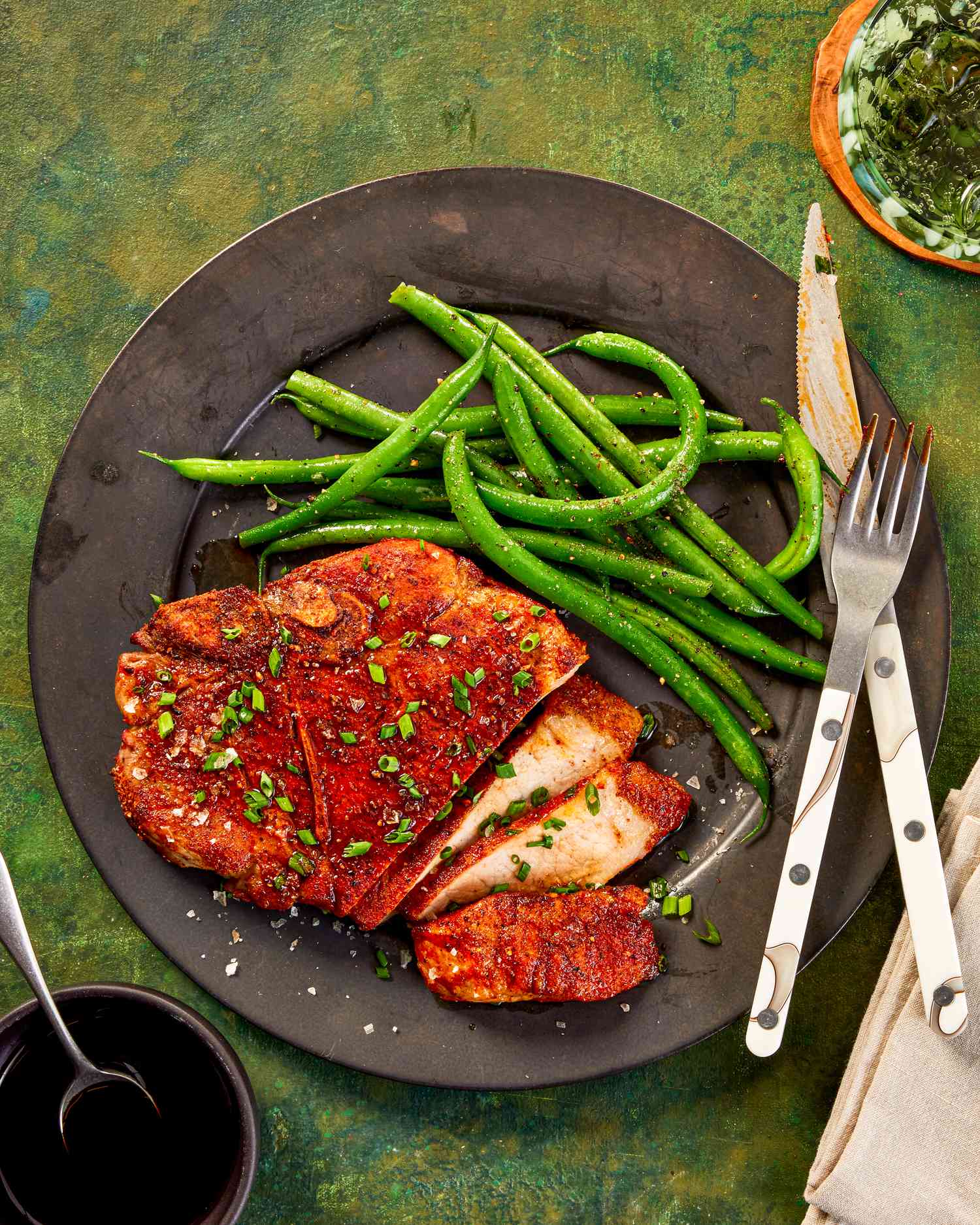 Pork chops on a plate with green beans.