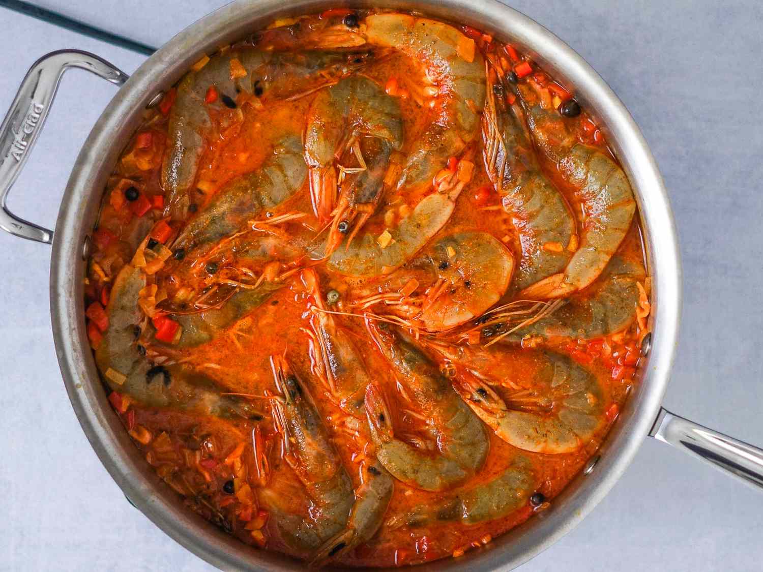 Shrimp added in one layer to the marinade mixture in the sauté pan.
