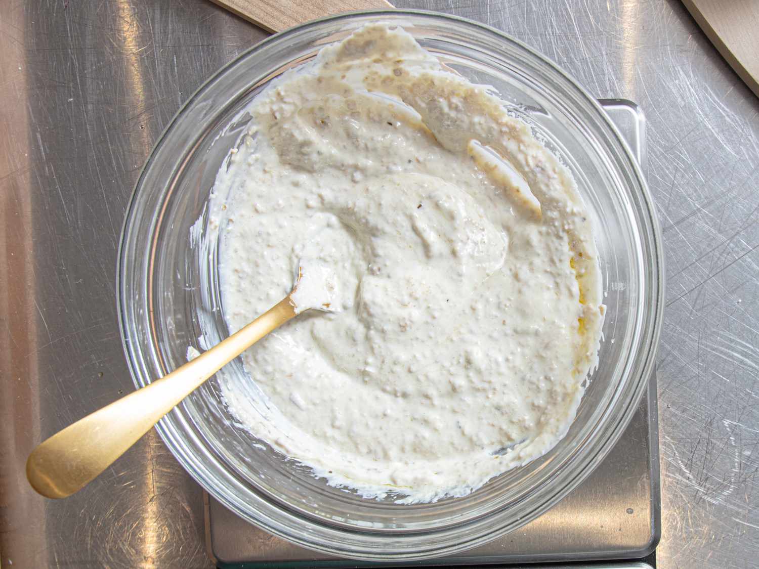 A bowl containing a creamy sauce mixture with a spoon, prepared for cooking