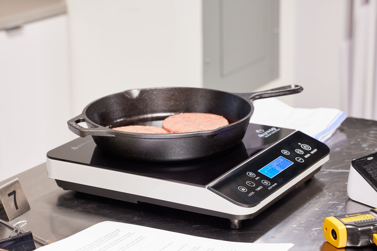 Two patties cooking in a skillet on an induction burner