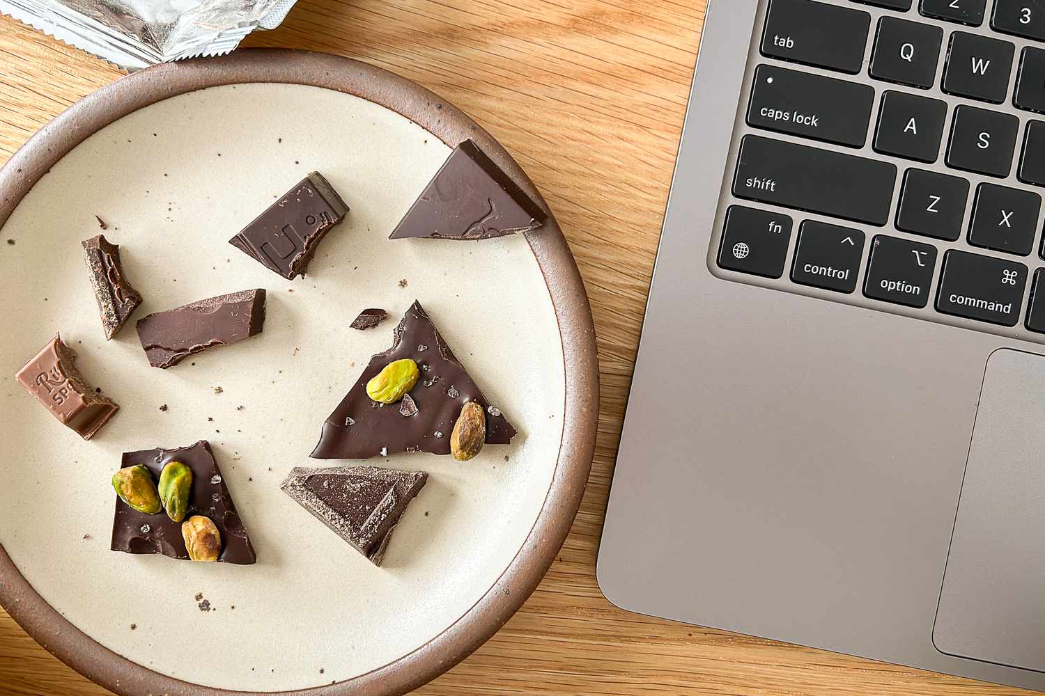 A small plate with pieces of chocolate bars on it sitting next to a laptop