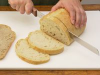 a person slicing bread on the winco cutting board