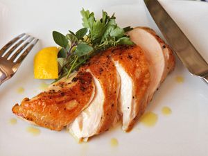 Sliced sous vide chicken breast on a plate, garnished with herbs and lemon.
