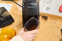 A person removes a tray from the Baratza ZCG495 Encore ESP Coffee Grinder