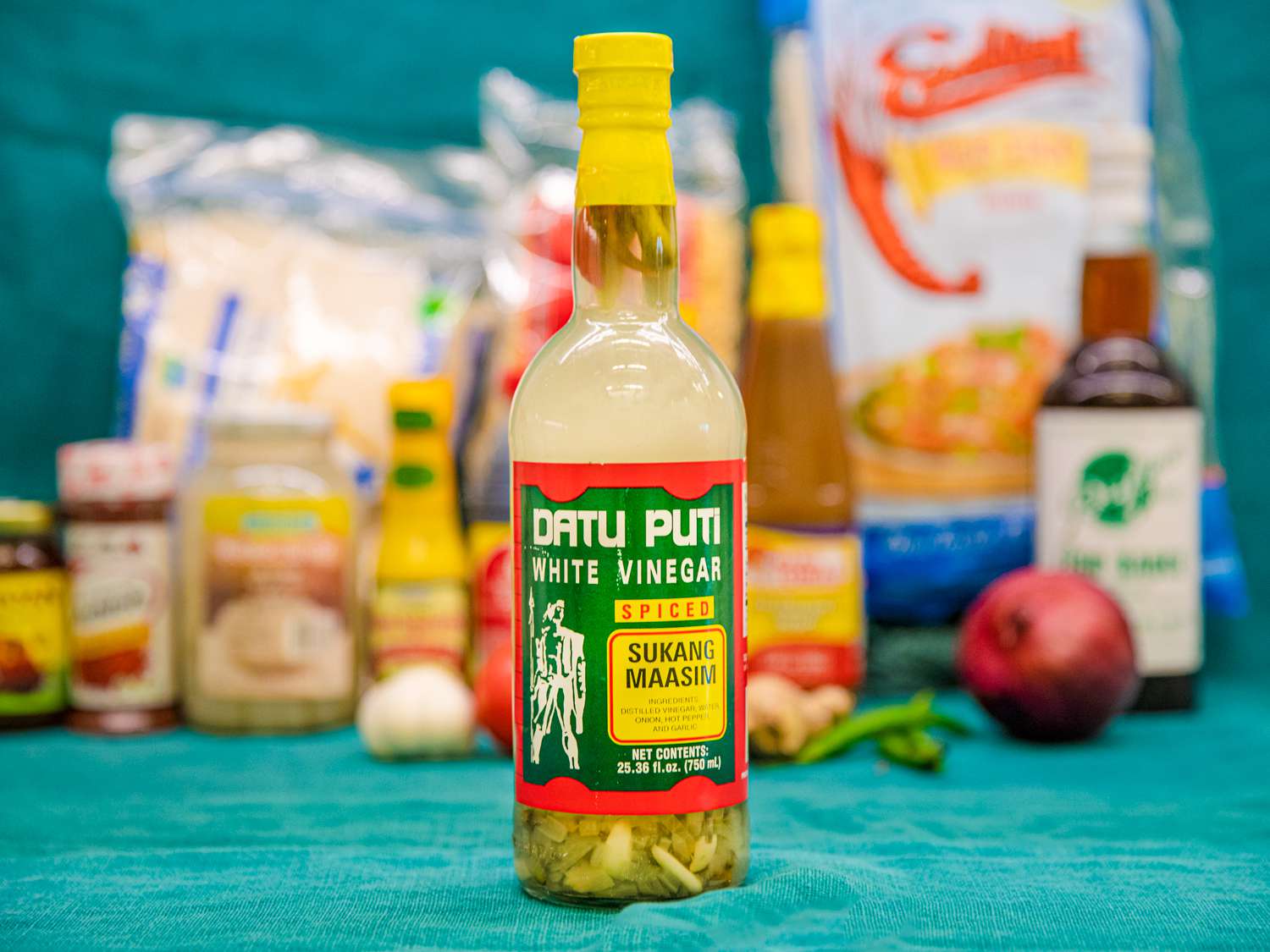 A bottle of Datu Puti White Vinegar on a blue backdrop