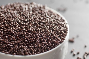 A white bowl filled to the brim with chocolate sprinkles.