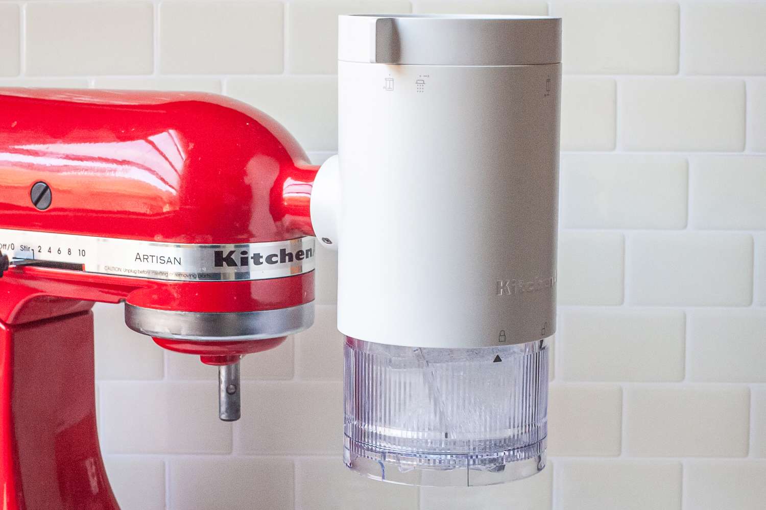 A red KitchenAid Artisan stand mixer with a white attachment installed on the side