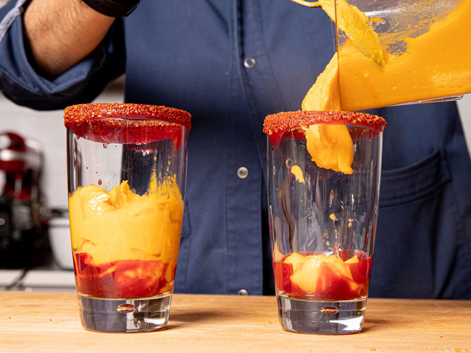 Frozen Alphonso mango puree being scraped into glasses for mangonadas