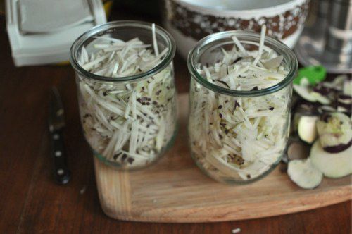 Kohlrabi matchsticks are divided evenly between two quart jars.
