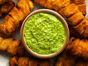 A close-up photo of a ceramic bowl holding guasacaca, surrounded by tequeÃ±os.