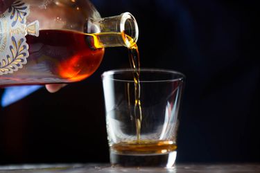 Amaro Nonino is poured from the bottle into a small glass. 