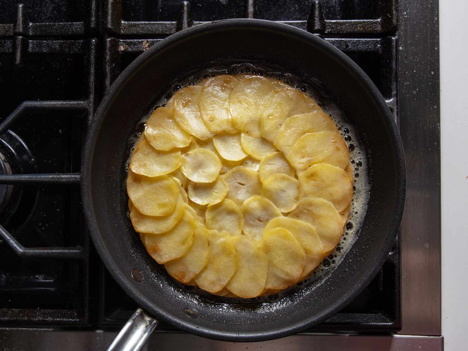 Frying the pommes anna in clarified butter to brown and crisp the presentation side.