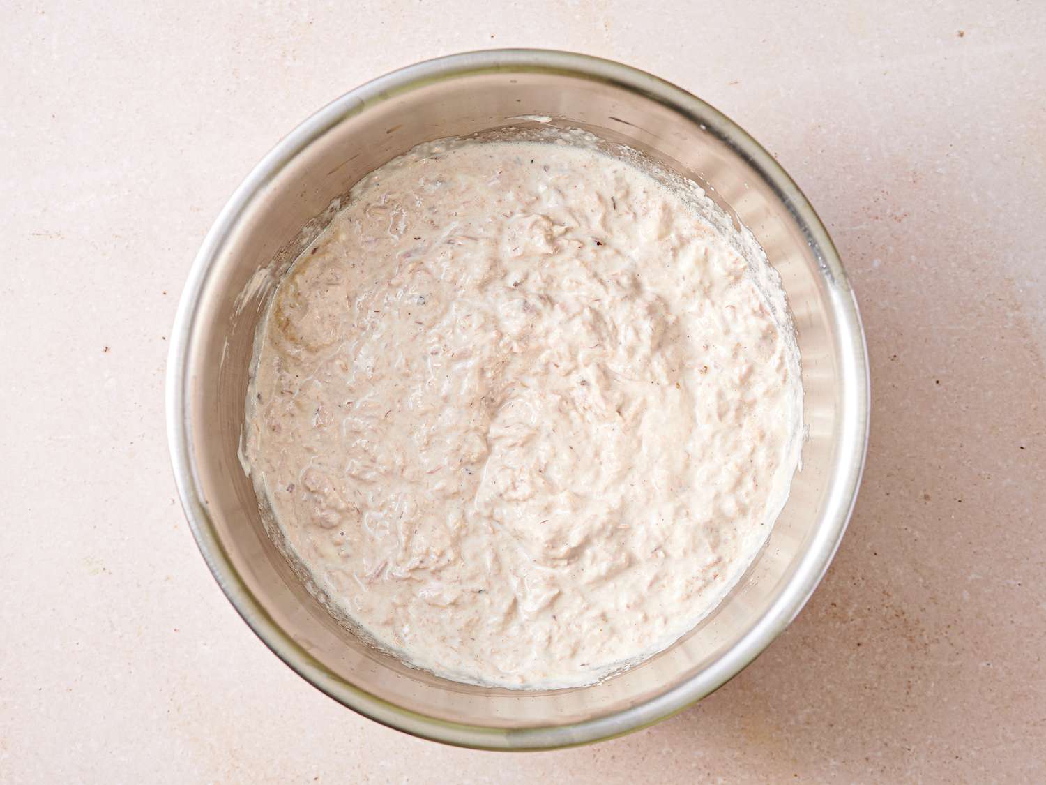 Tuna and mayonnaise mixed inside a medium bowl