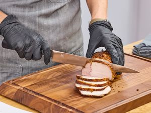 A person slices meat using the Miyabi Koh 9.5 Inch Slicing Knife