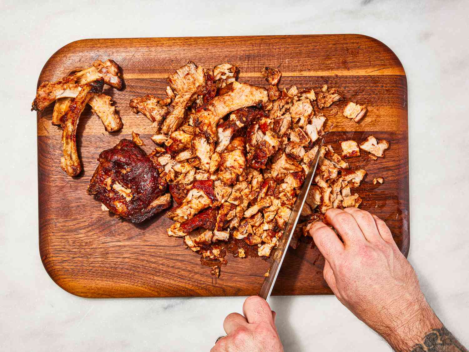 Overhead view of chopping ribs on a wooden cutting board.