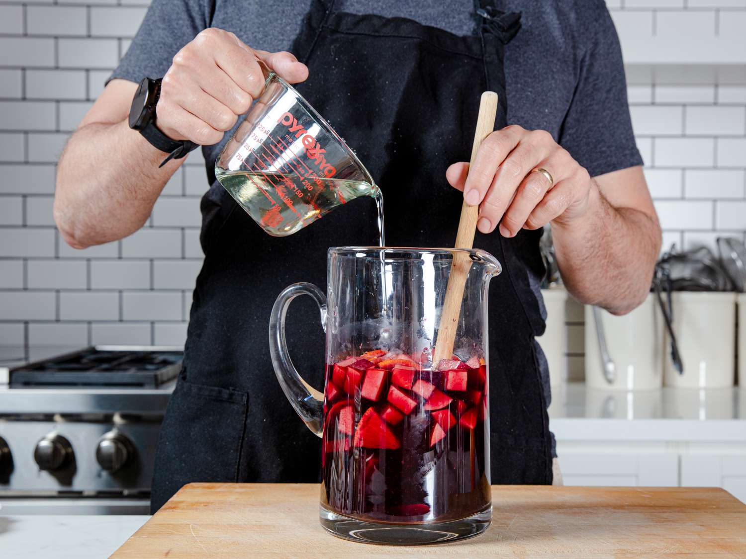 Author stirring simple syrup into a pitcher of sangria.