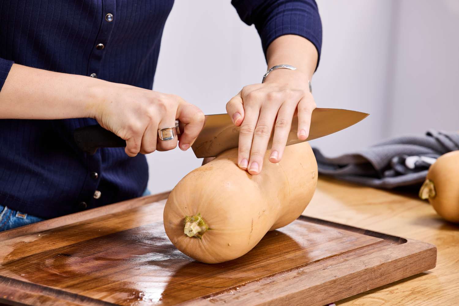 A person cutting into a butternut squash with the Mercer Culinary 8-Inch Genesis Chef's Knife