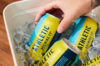a hand pulling a can of athletic run wild beer from a bucket of ice