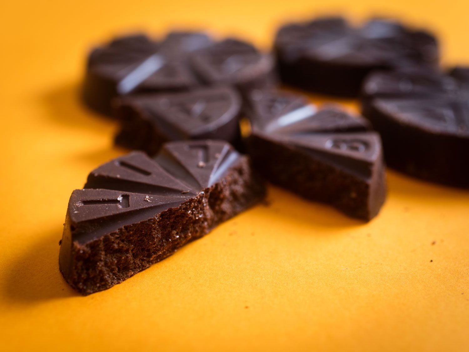 Close-up of several broken disks of Mexican chocolate against an orange background