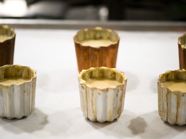 Canele molds filled with batter ready for baking