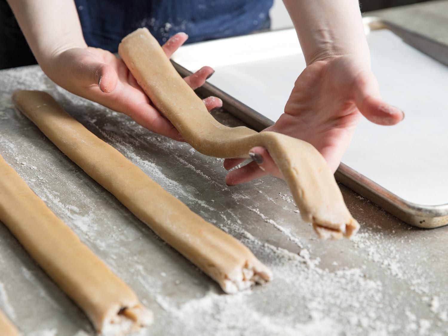 Carefully transferring filled newton strips to baking sheet.