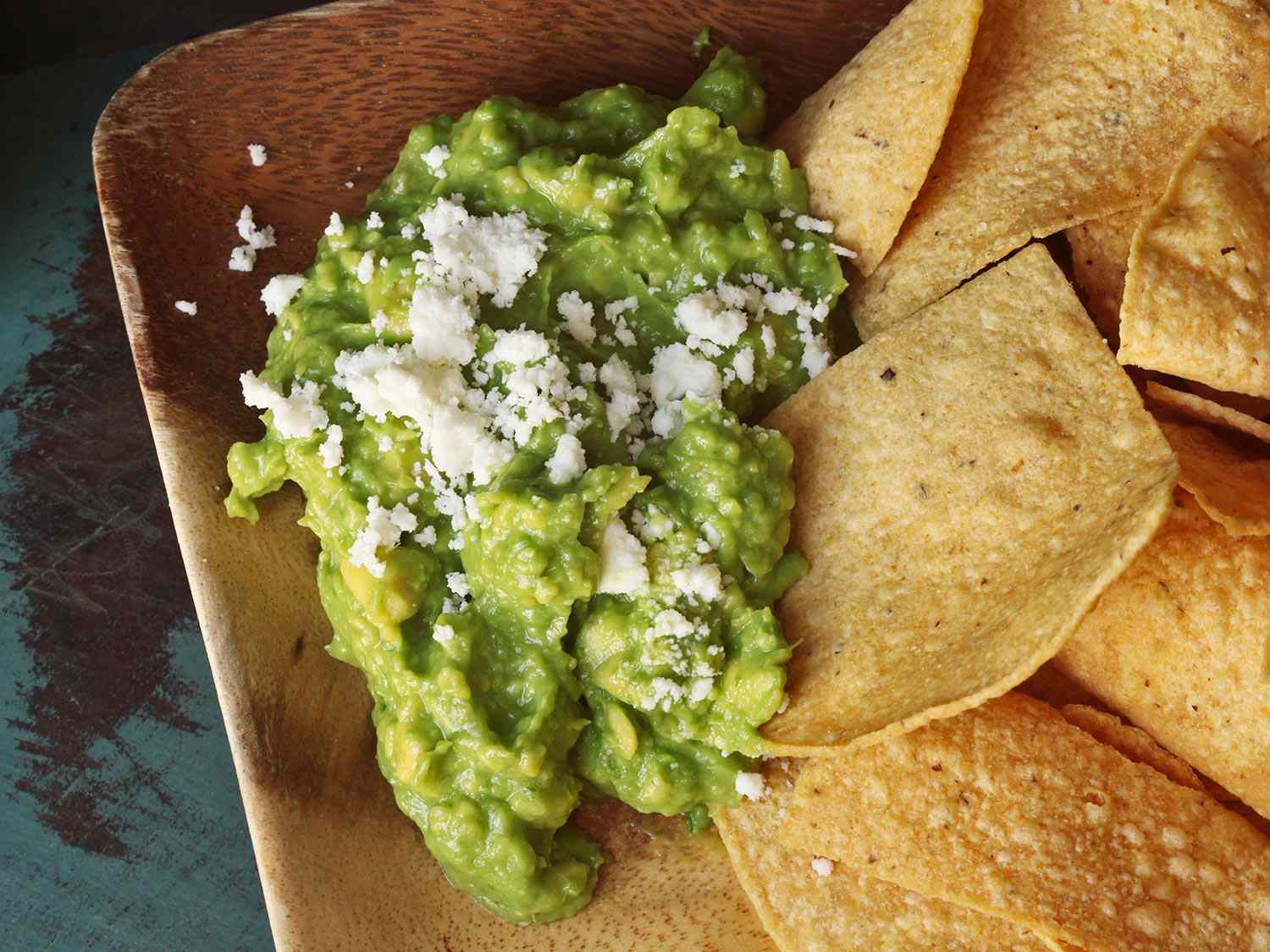 Guacamole on wooden platter with tortilla chips