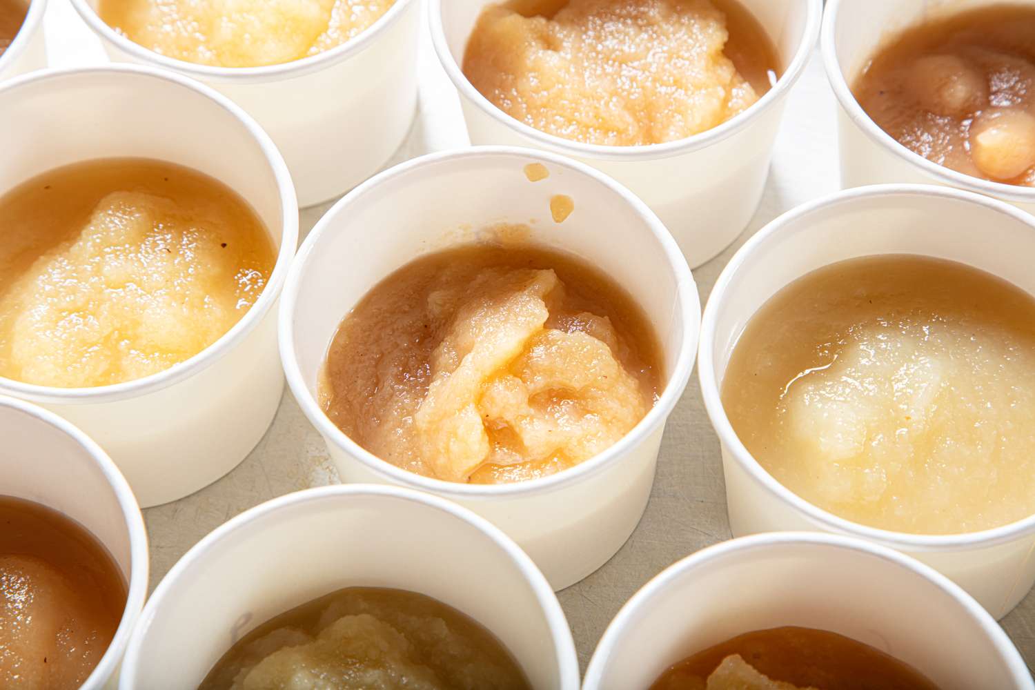 Multiple cups filled with applesauce arranged in a grid pattern