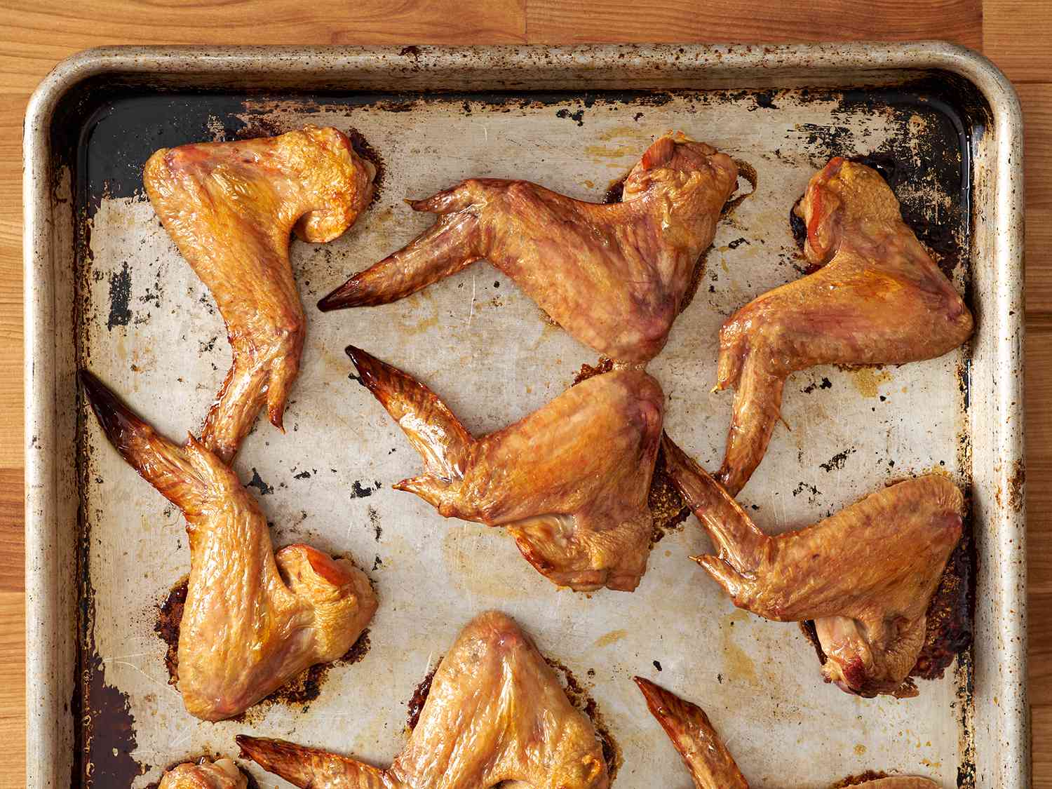 Browned chicken wings laid out on a baking sheet.