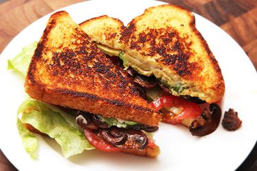 A vegan B.L.A.T. sandwich halved and served on a white plate.