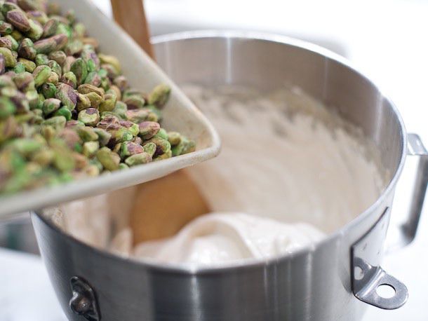 Warmed pistachios are added to the meringue from a sheetpan.