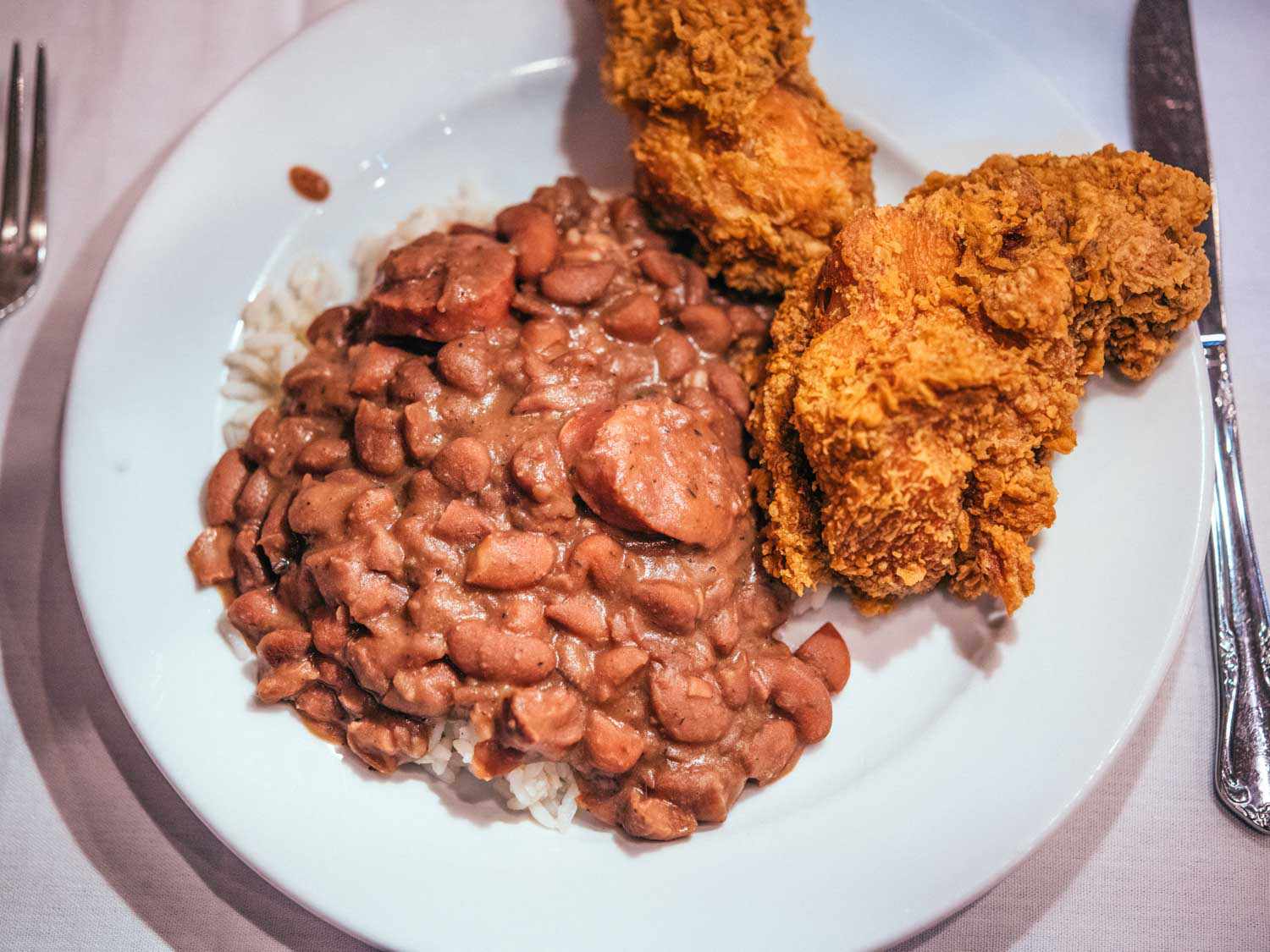 Red bean, rice, gravy and fried chicken on a plate.