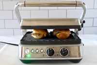 Two sandwiches cooking on a Breville panini press.