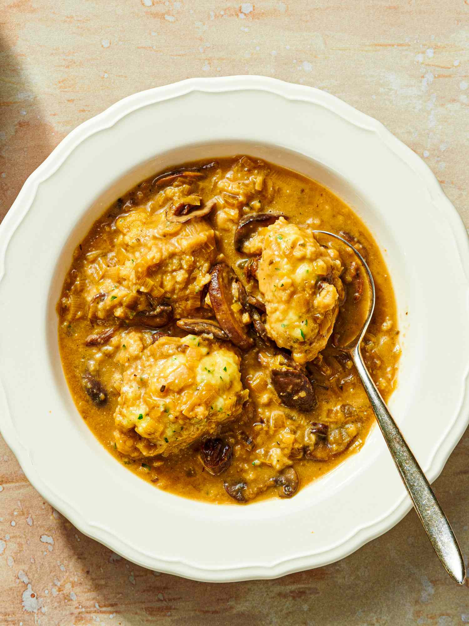 A bowl of mushroom and dumpling soup with a spoon