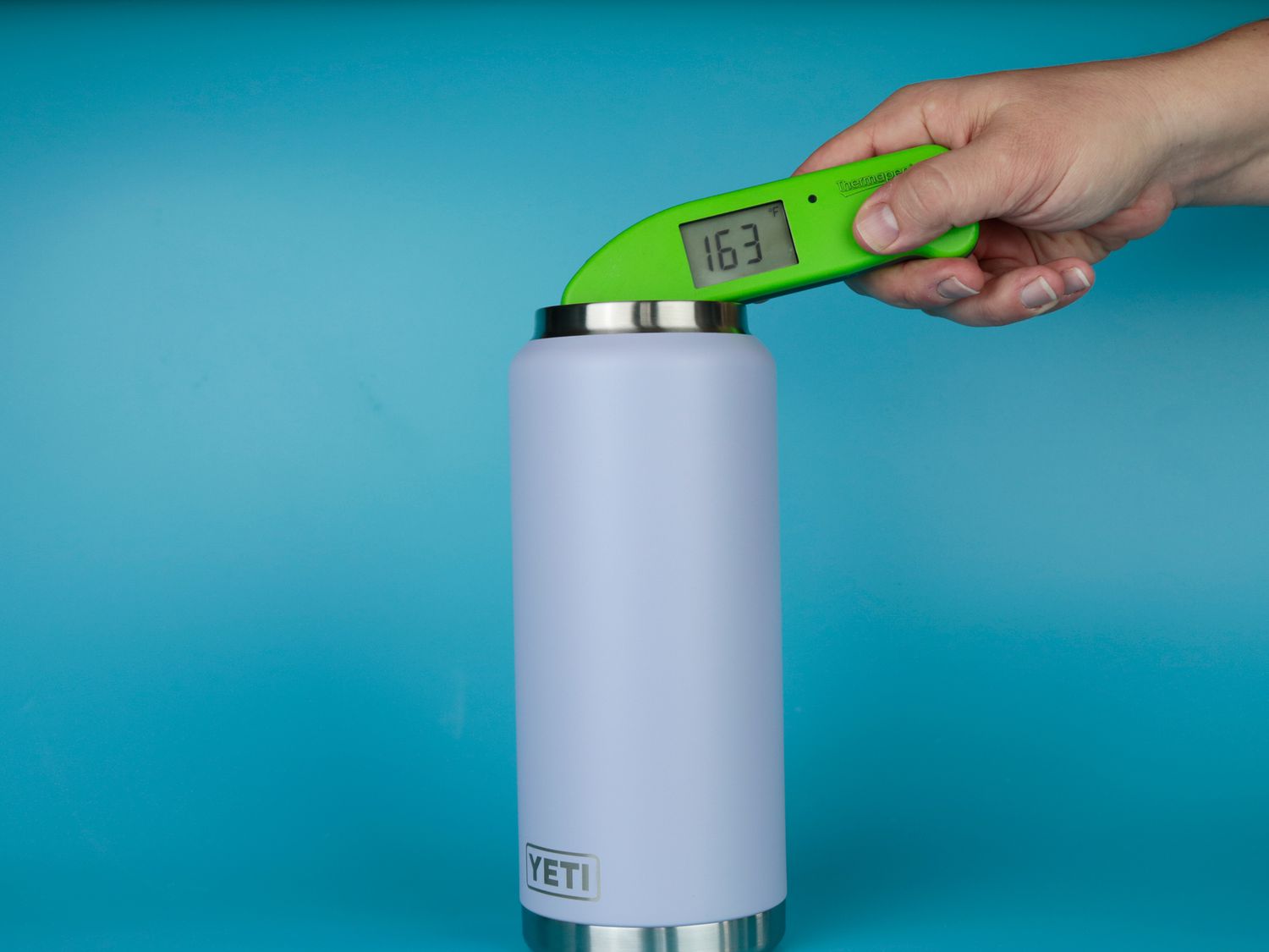 A person using a Thermapen to take the temperature of hot water inside of a thermos