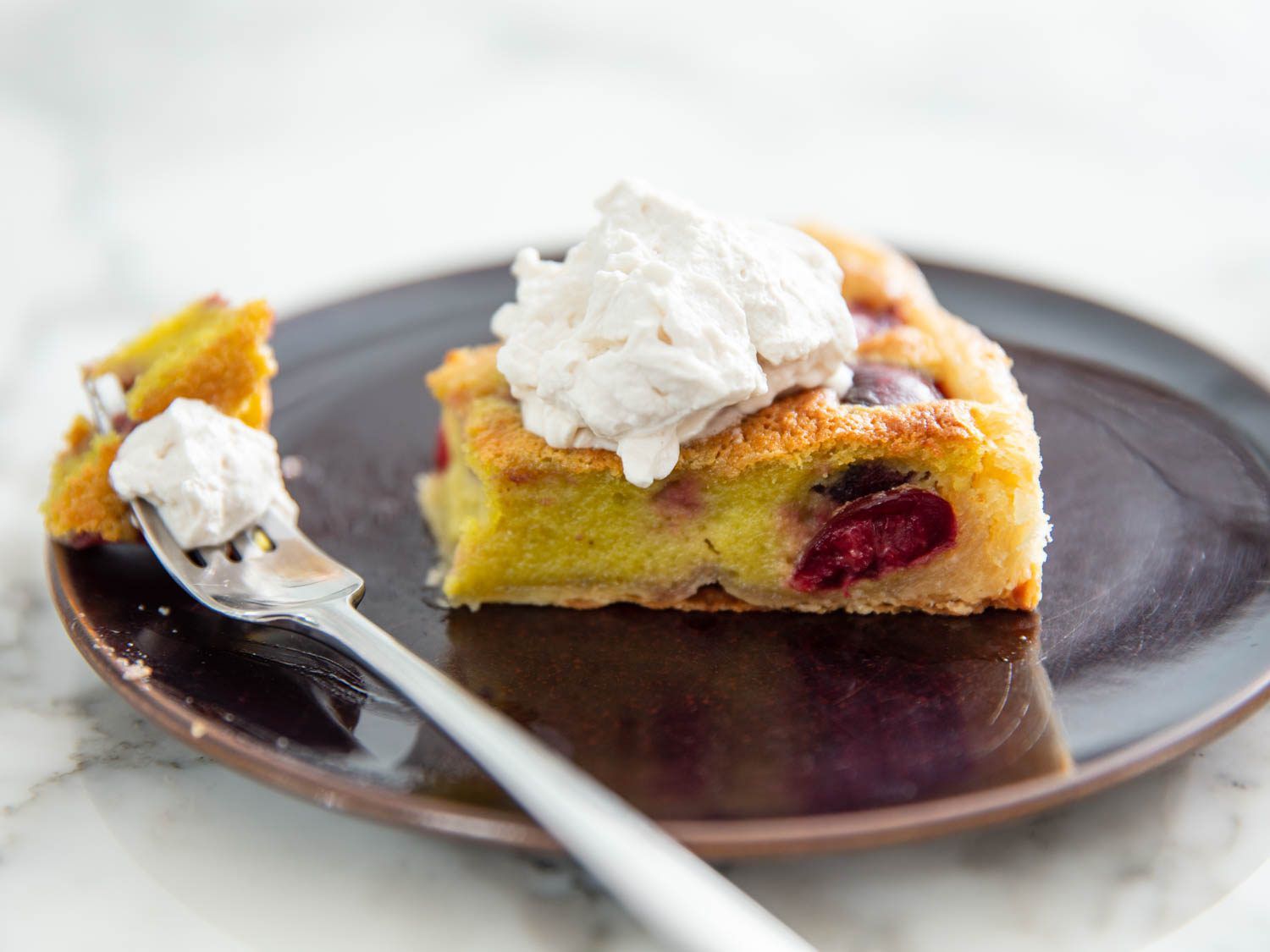 slice of cherry pistachio frangipane tart with a bite missing