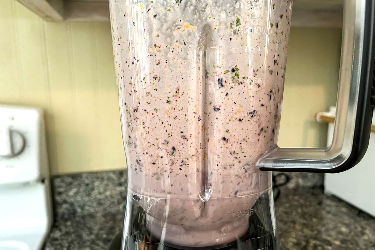 A closeup of a poorly-blended berry and kale smoothie in a blender.