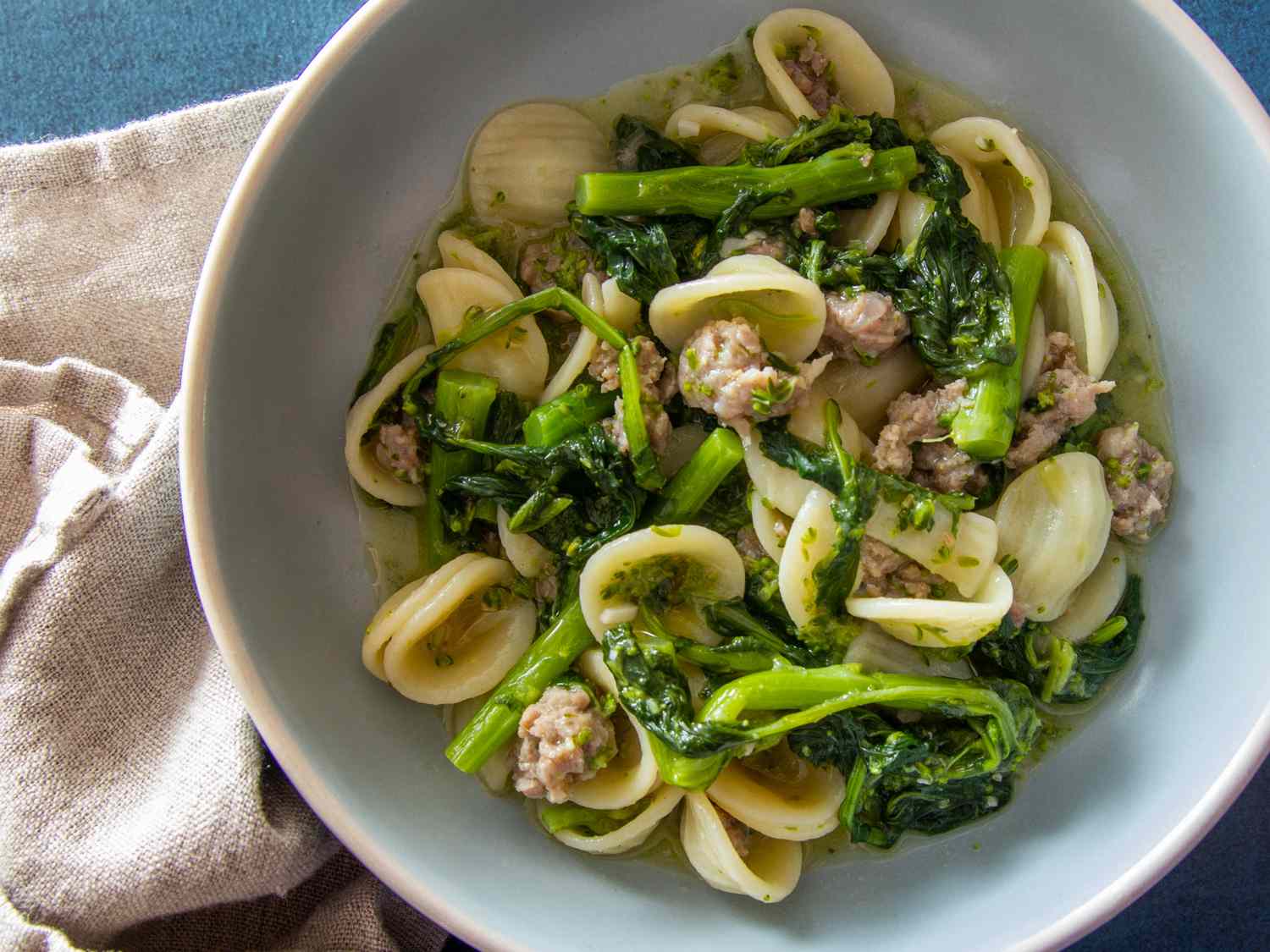 Orecchiette con Salsiccia e Cime di Rapa in a light blue bowl