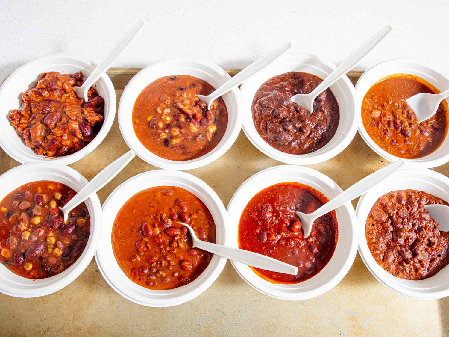 Assorted bowls of vegetarian chili with spoons showing different textures and ingredients