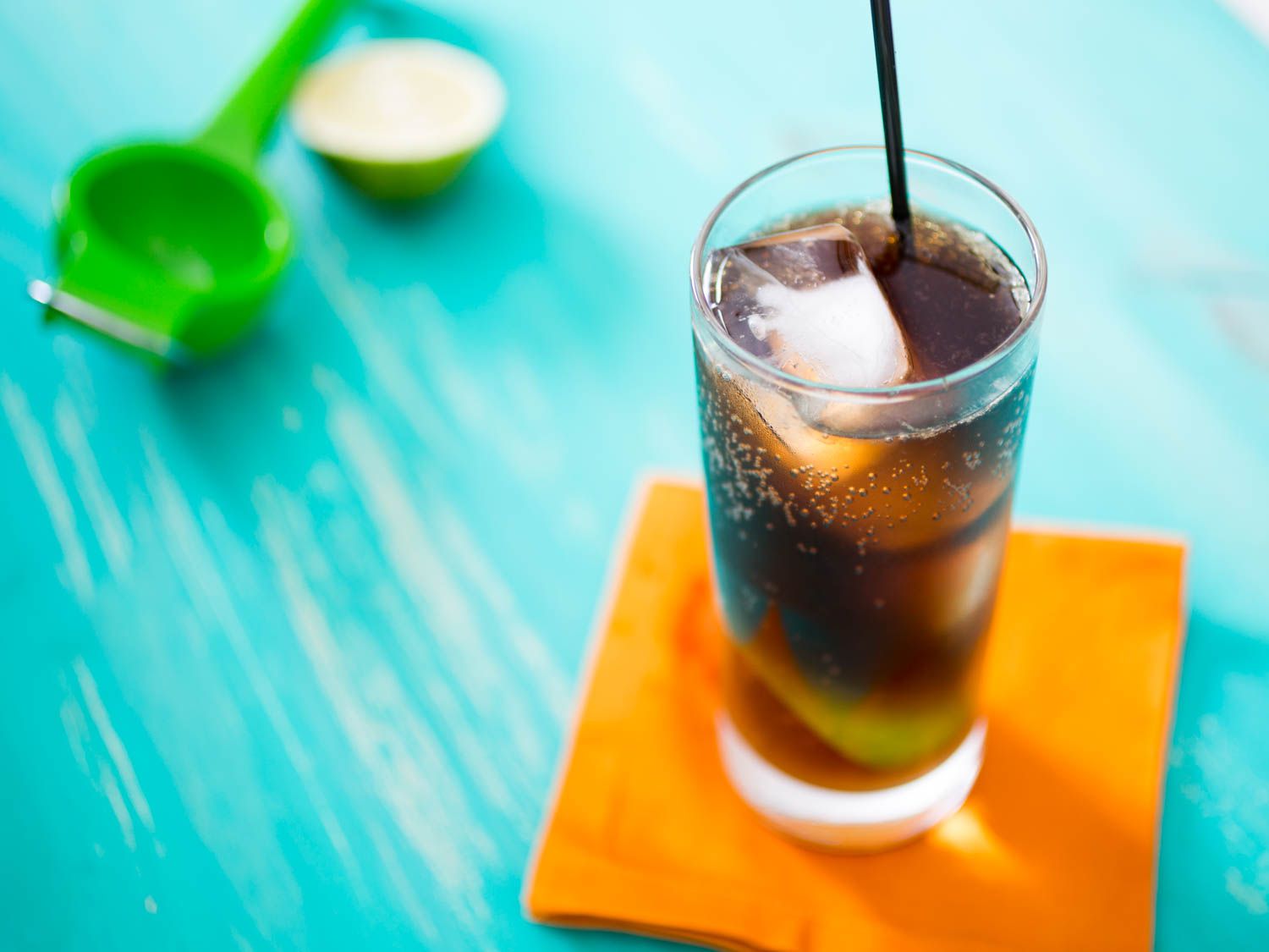 Cuba libre over ice in a tall glass with a straw