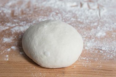 a ball of pizza dough on a floured work surface