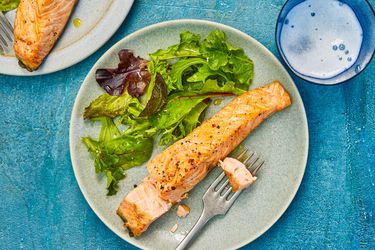 Overhead view of air-fryer salmon, served on an earthenware plate with a simple green salad.