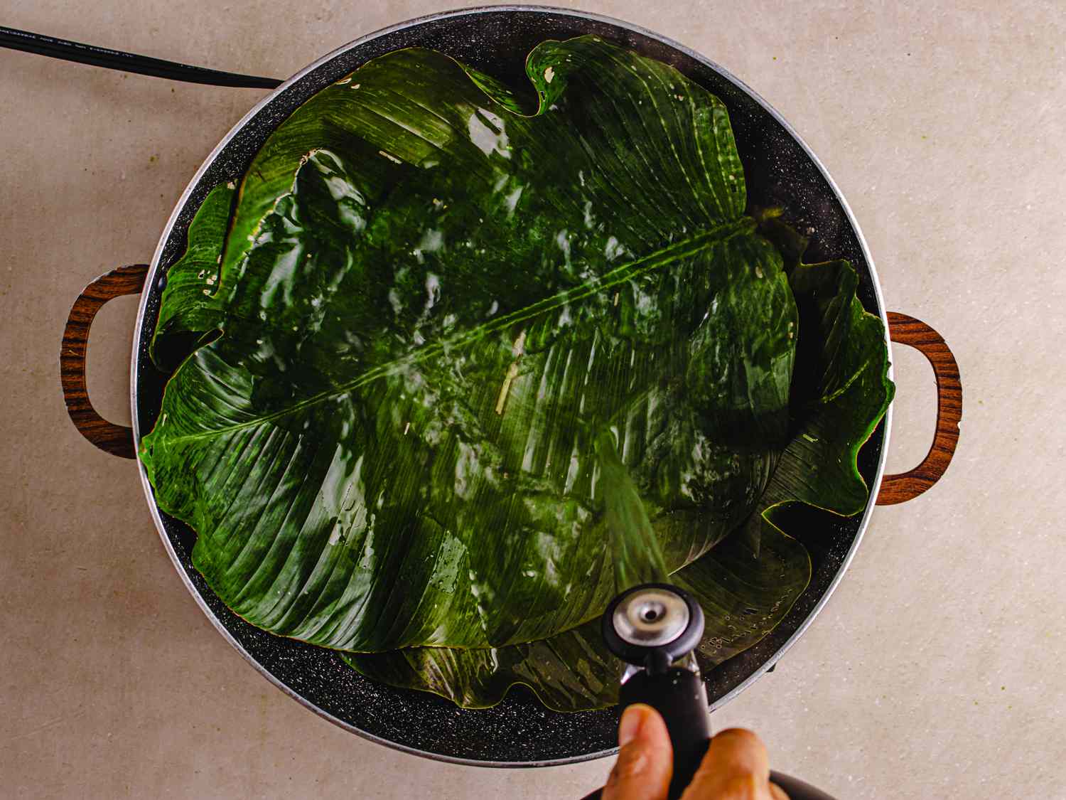 Overhead view of pouring hot water into moin moin leaves