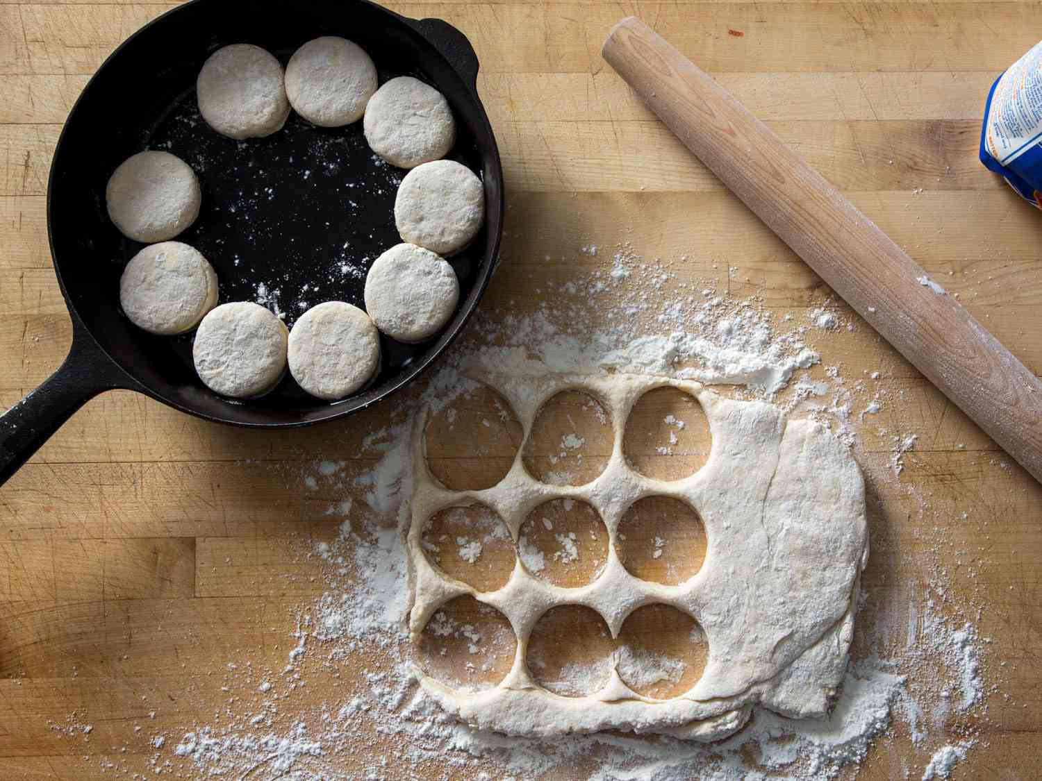 Biscuits cut out and arranged in a skillet with a French rolling pin sitting beside them.