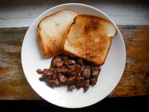 Overhead view of deviled kidneys served with two pieces of white toast.