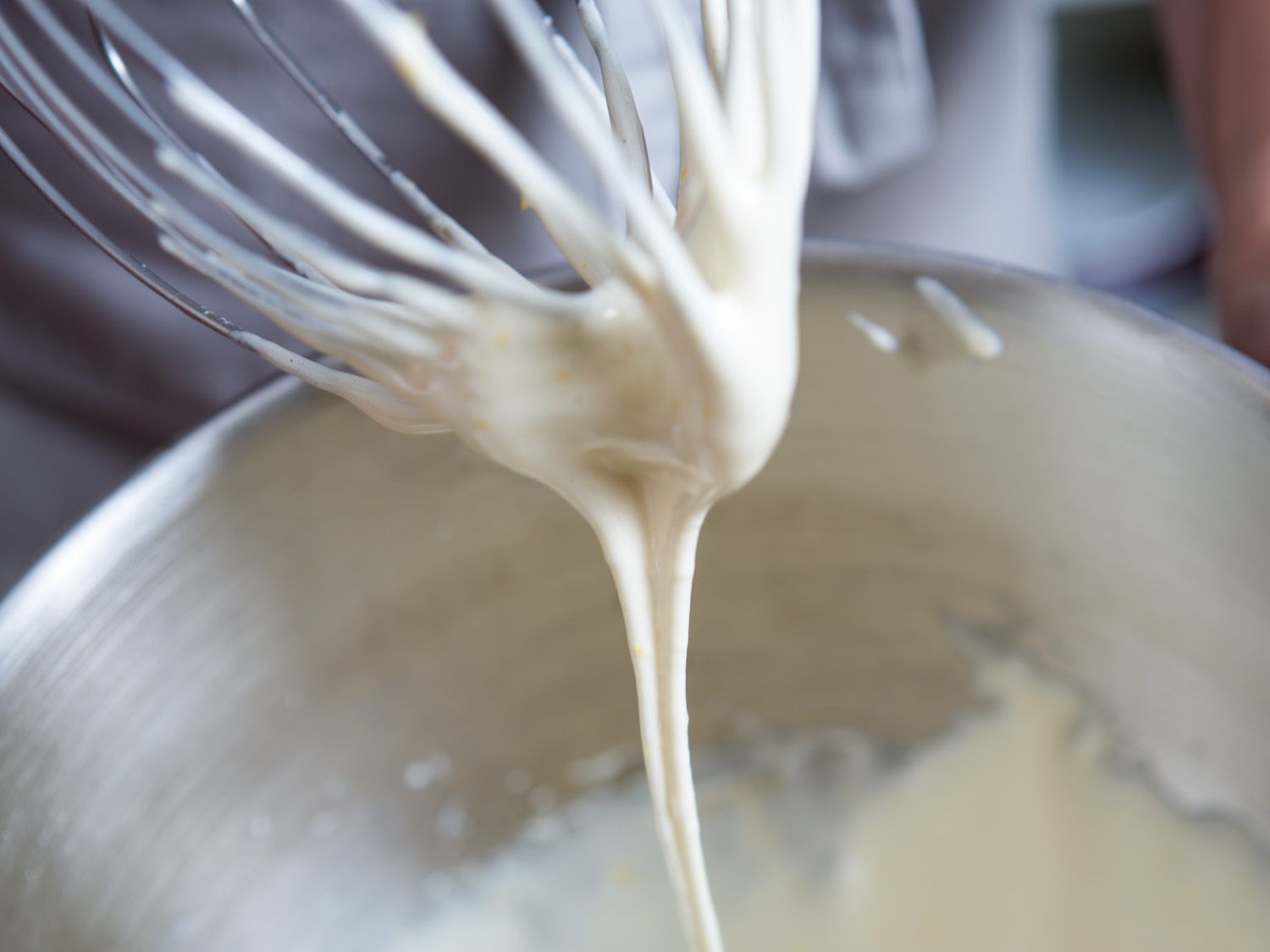 Close-up egg whipped to ribbon stage falling off whisk attachment of mixer