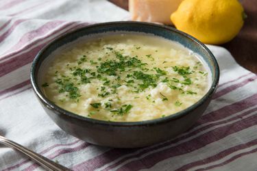 A bowl of stracciatella soup resting on a striped dishcloth.