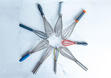 Nine whisks arranged in a circle on a white marble countertop